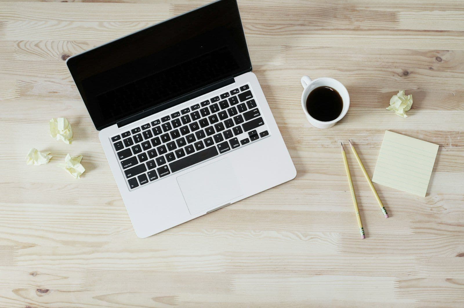Turned off MacBook Pro beside white ceramic mug filled with coffee, illustrating credit-Builder Loans.