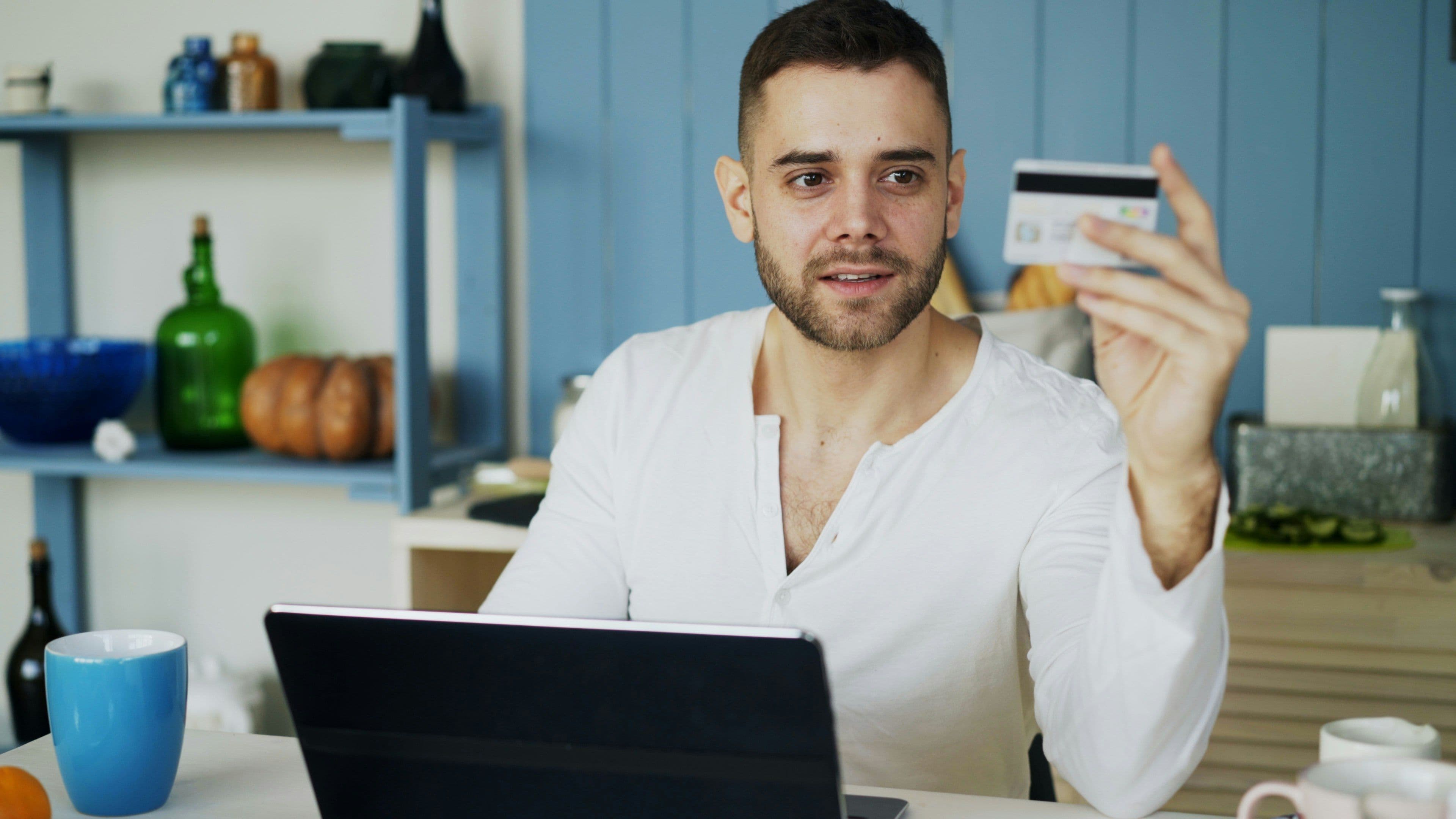 Man holding a credit card while shopping online on a laptop