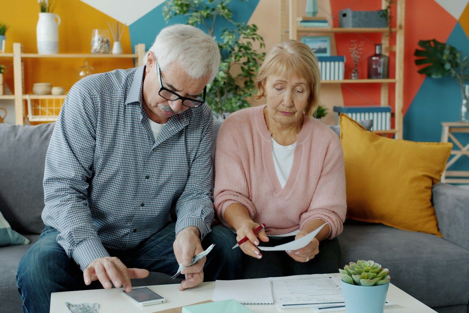 An older couple on a sofa going over bills with a calculator