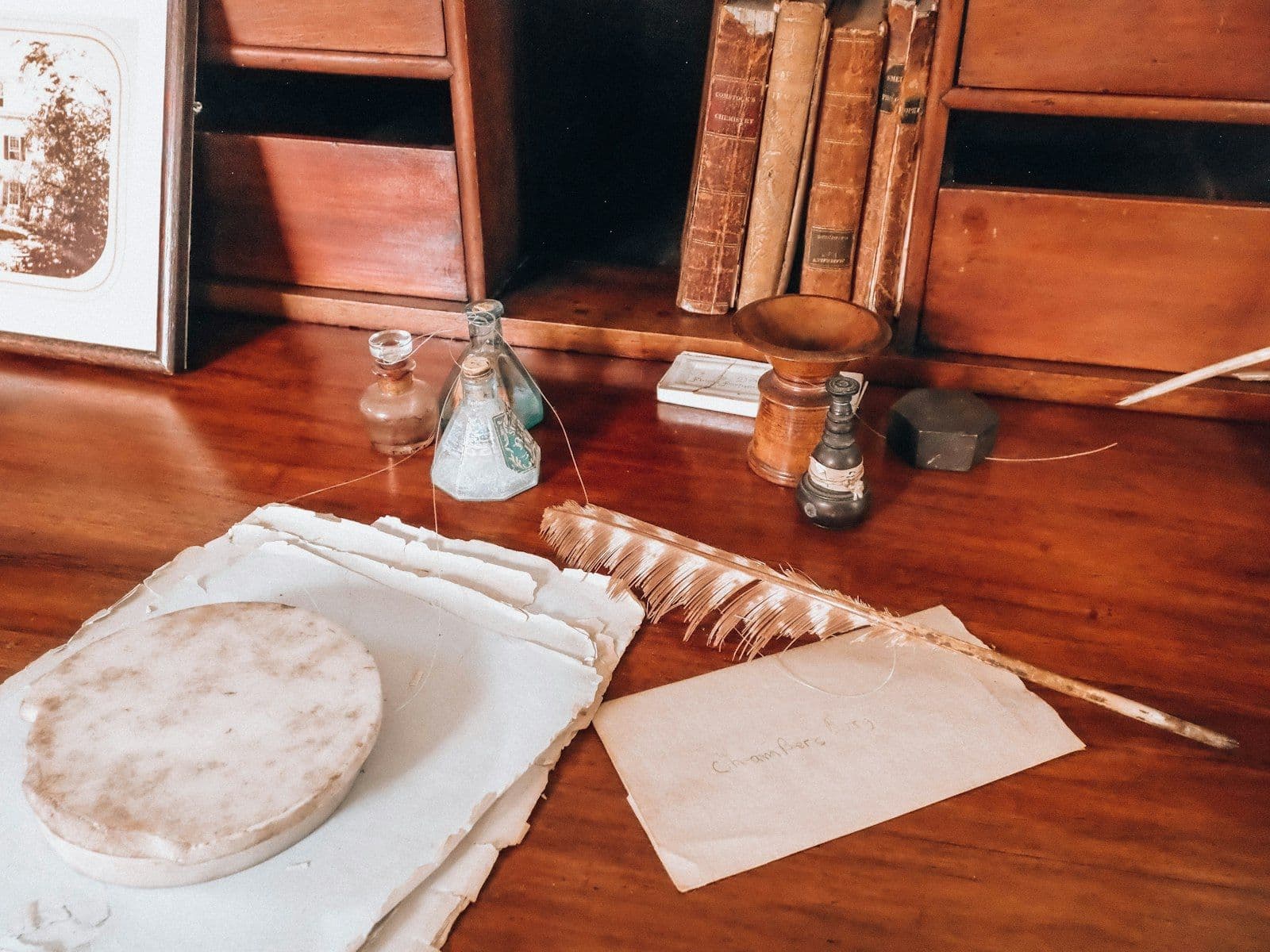 Antique wooden desk with quill pen, old papers, and inkwells, illustrating how to Write a Goodwill Letter.