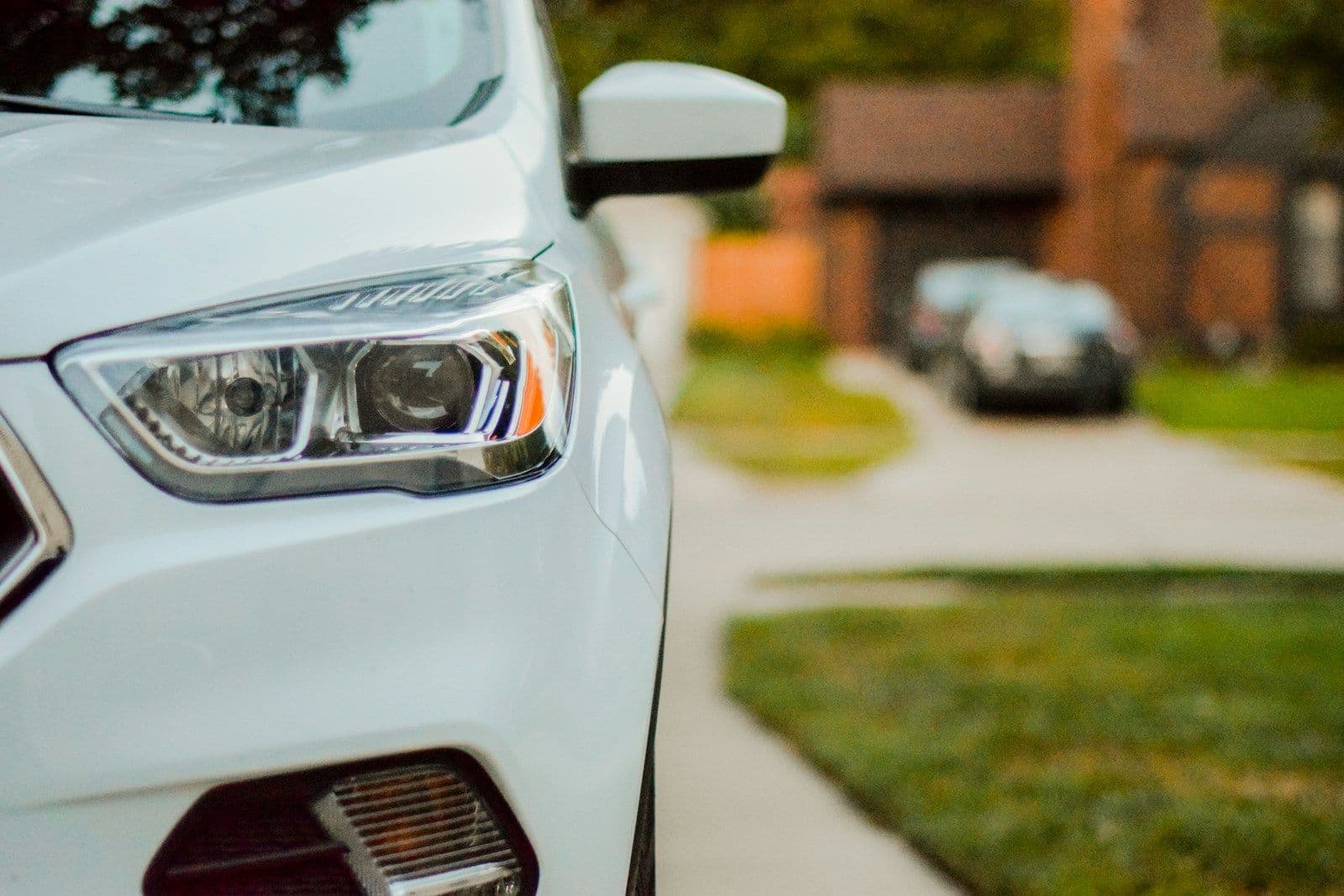 A white car parked at the curb on a quiet residential street