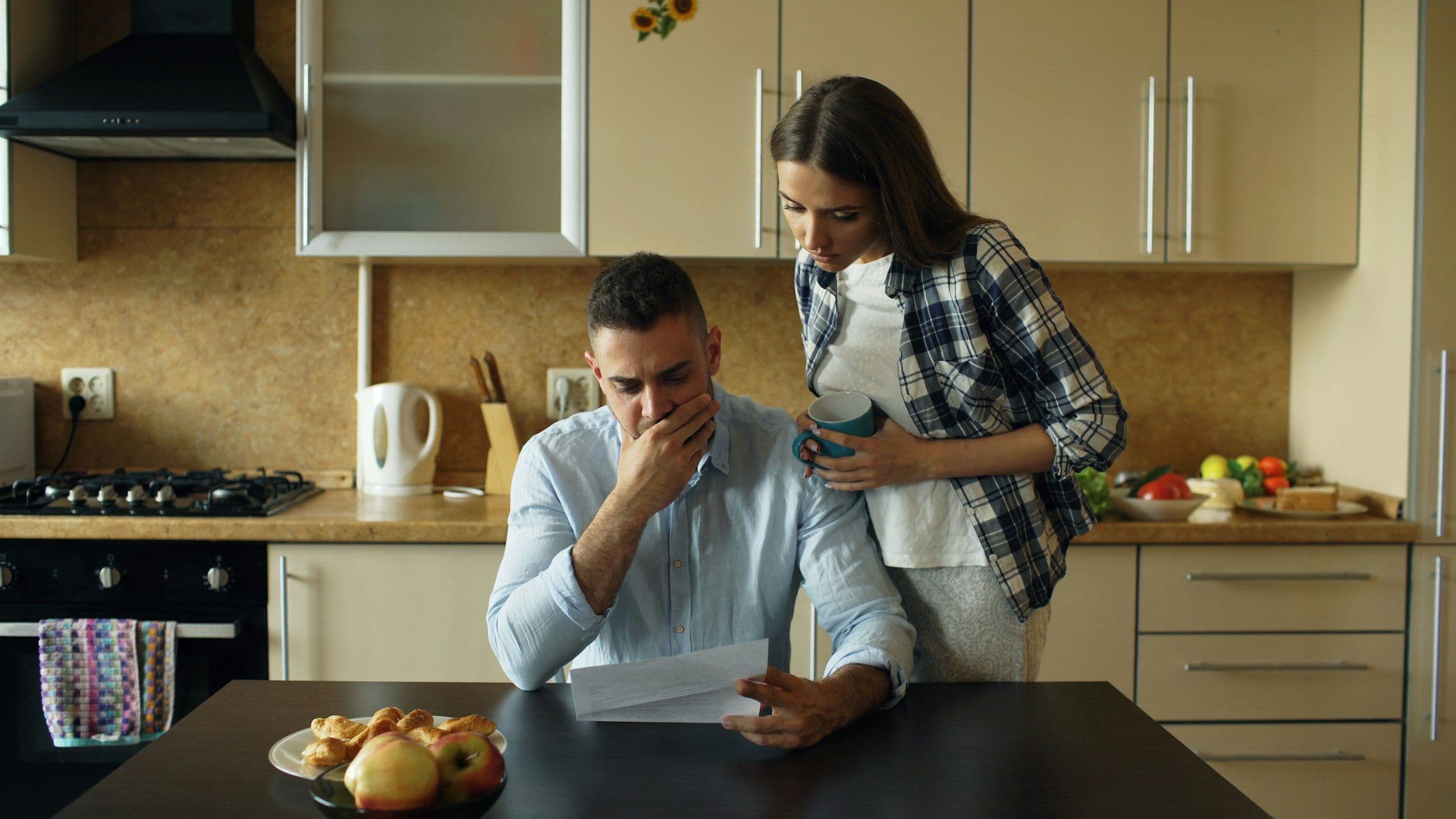 Couple reviewing unpaid bills at a kitchen table