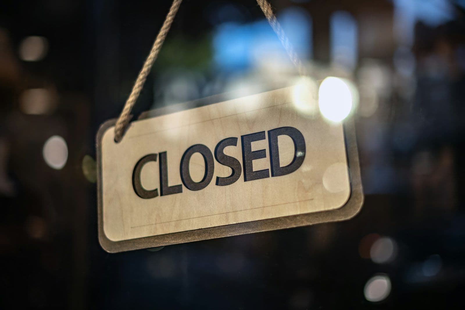 A closed sign hanging in a shop window, illustrating closed accounts on a credit report.