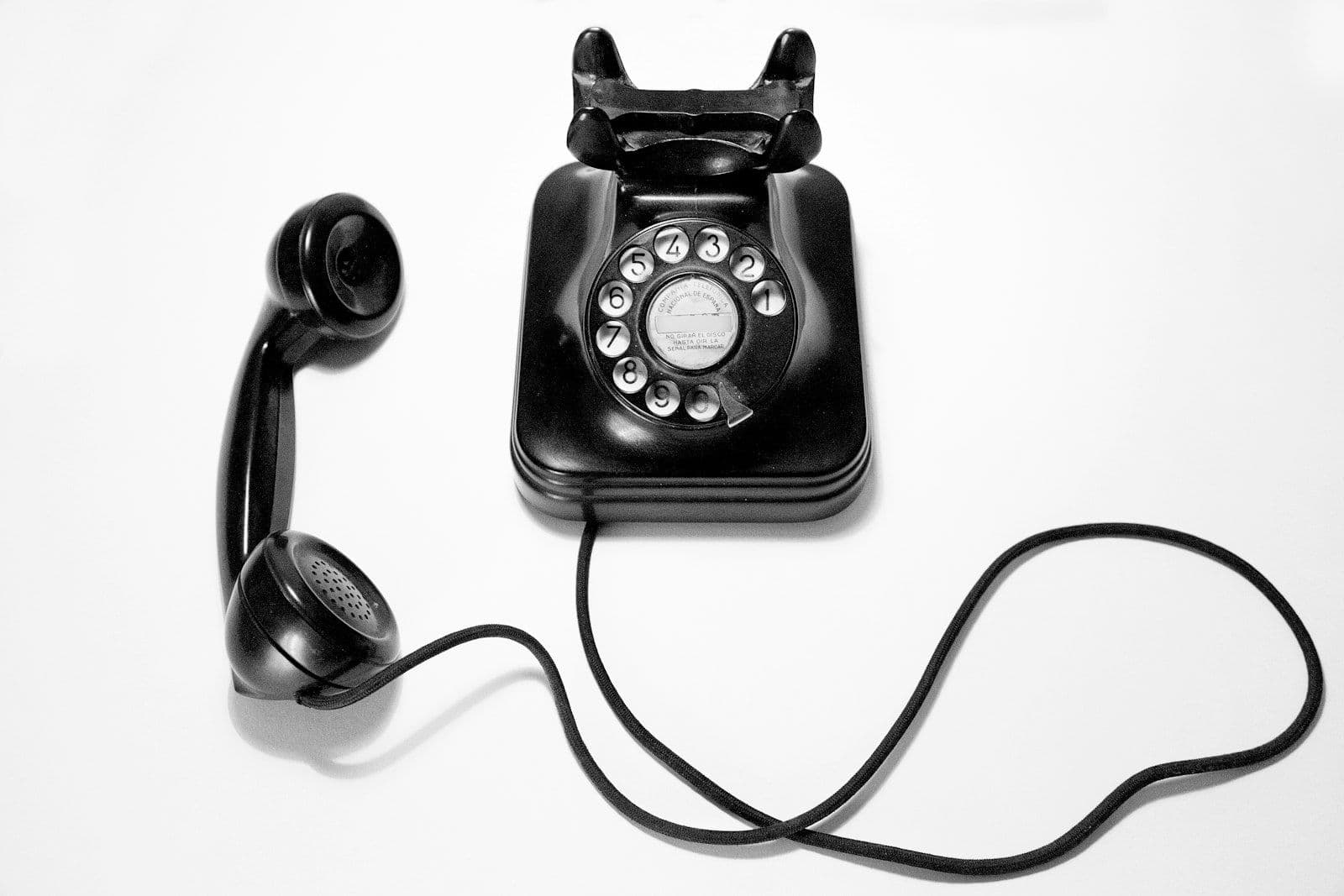 Black rotary dial telephone on a white surface, illustrating stopping debt collector contact under the FDCPA.