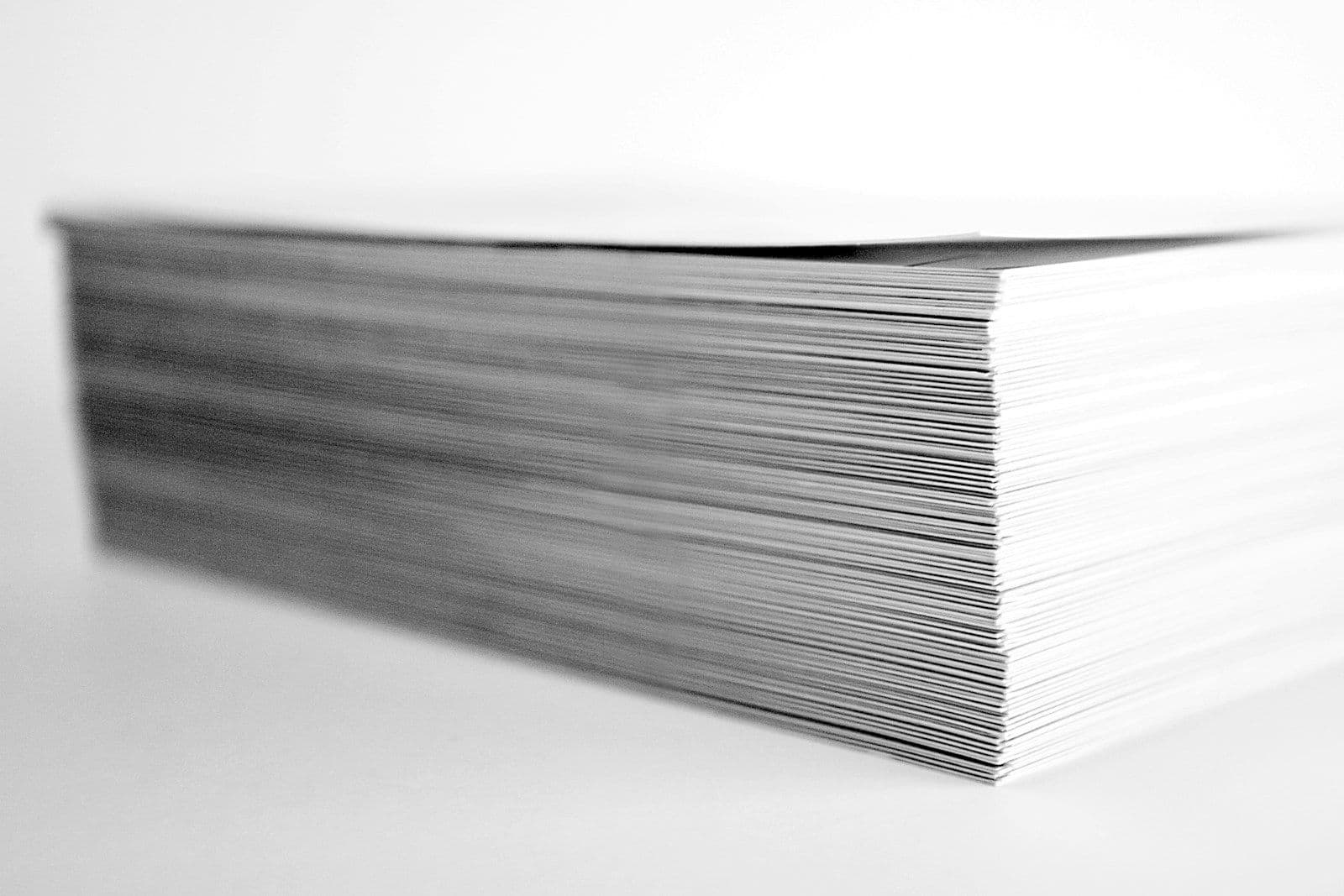 Neat stack of blank white papers viewed from the side on a plain background
