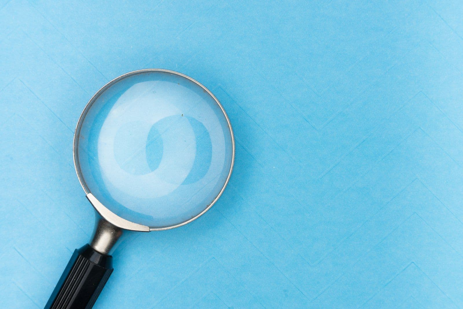 Magnifying glass over documents, illustrating investigating an unrecognized account on a credit report.