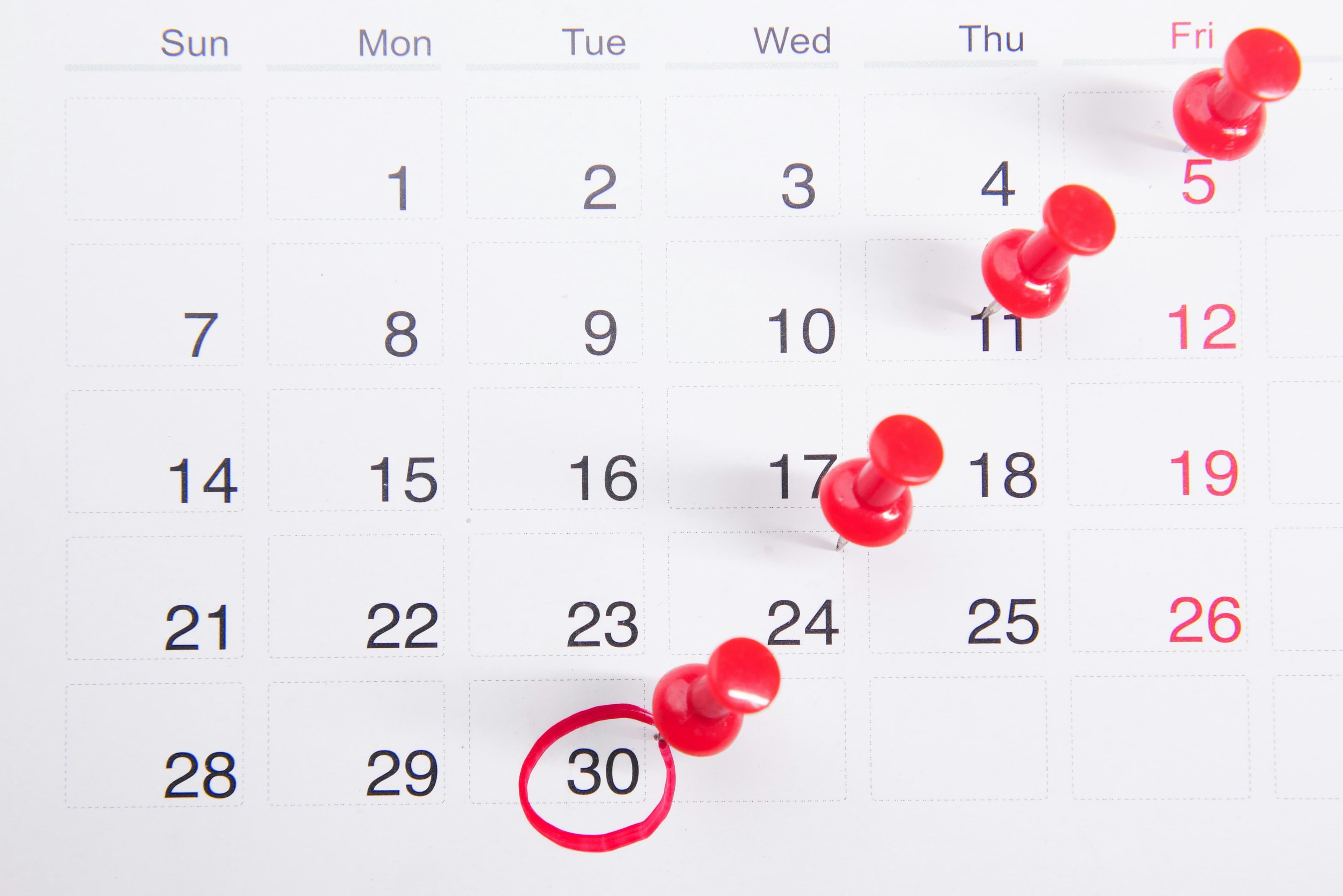 Calendar with red pushpins marking dates and a red circle around the number 30.