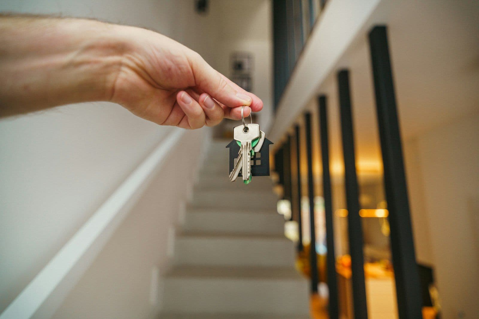 Here's a possible caption: keys being held in front of a staircase, illustrating tenant Screening Reports.