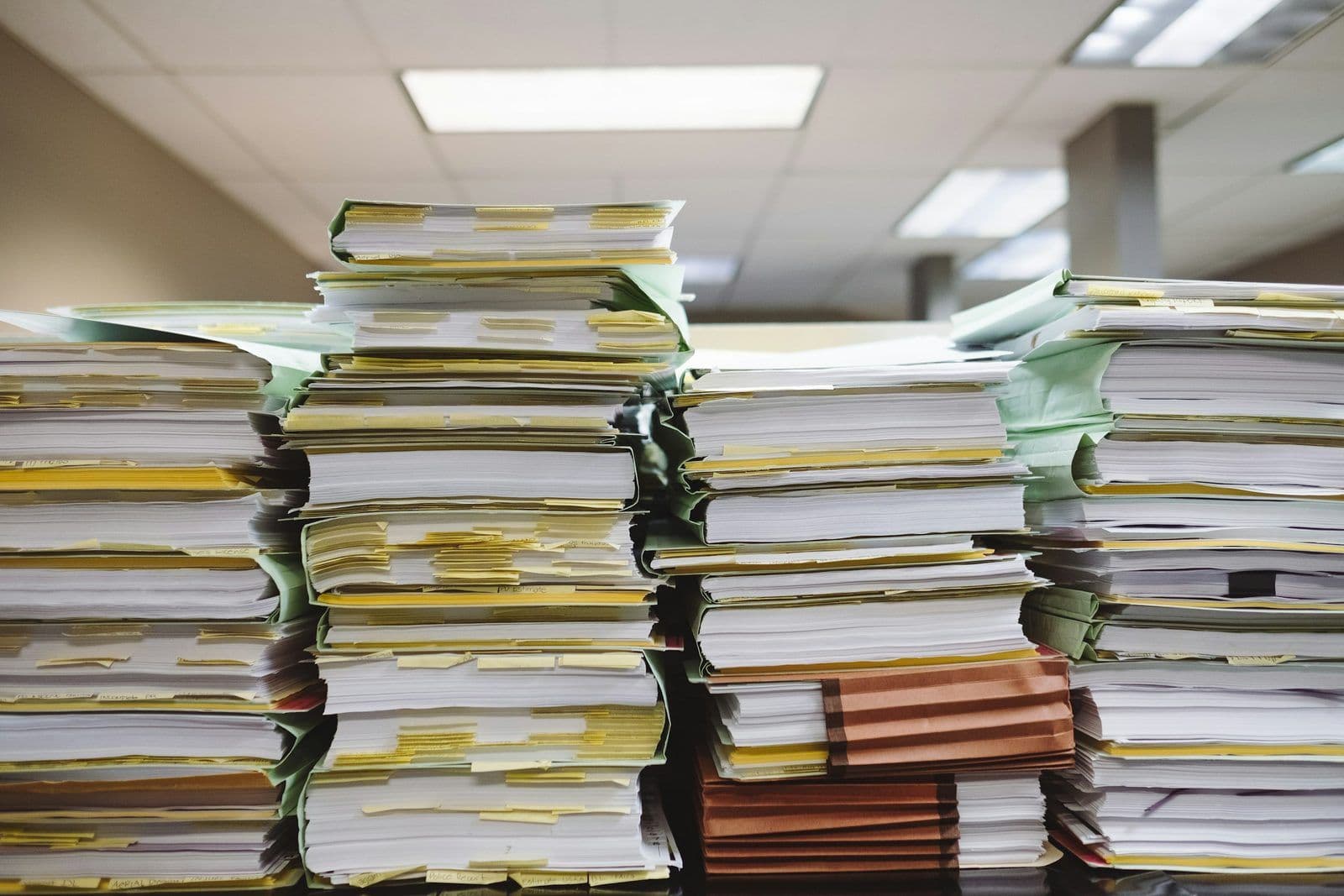Stacks of paper files and folders, illustrating collection account records on a credit report.