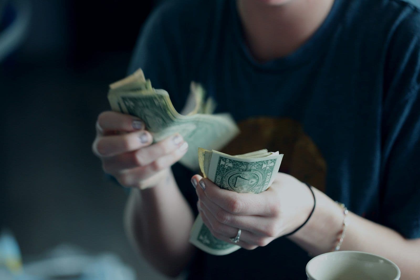 A person counting dollar bills, illustrating how a personal loan affects a credit score.