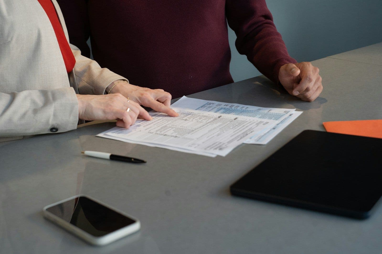 A hand tracing a line across stacked financial forms, illustrating one account reported differently on each credit report.