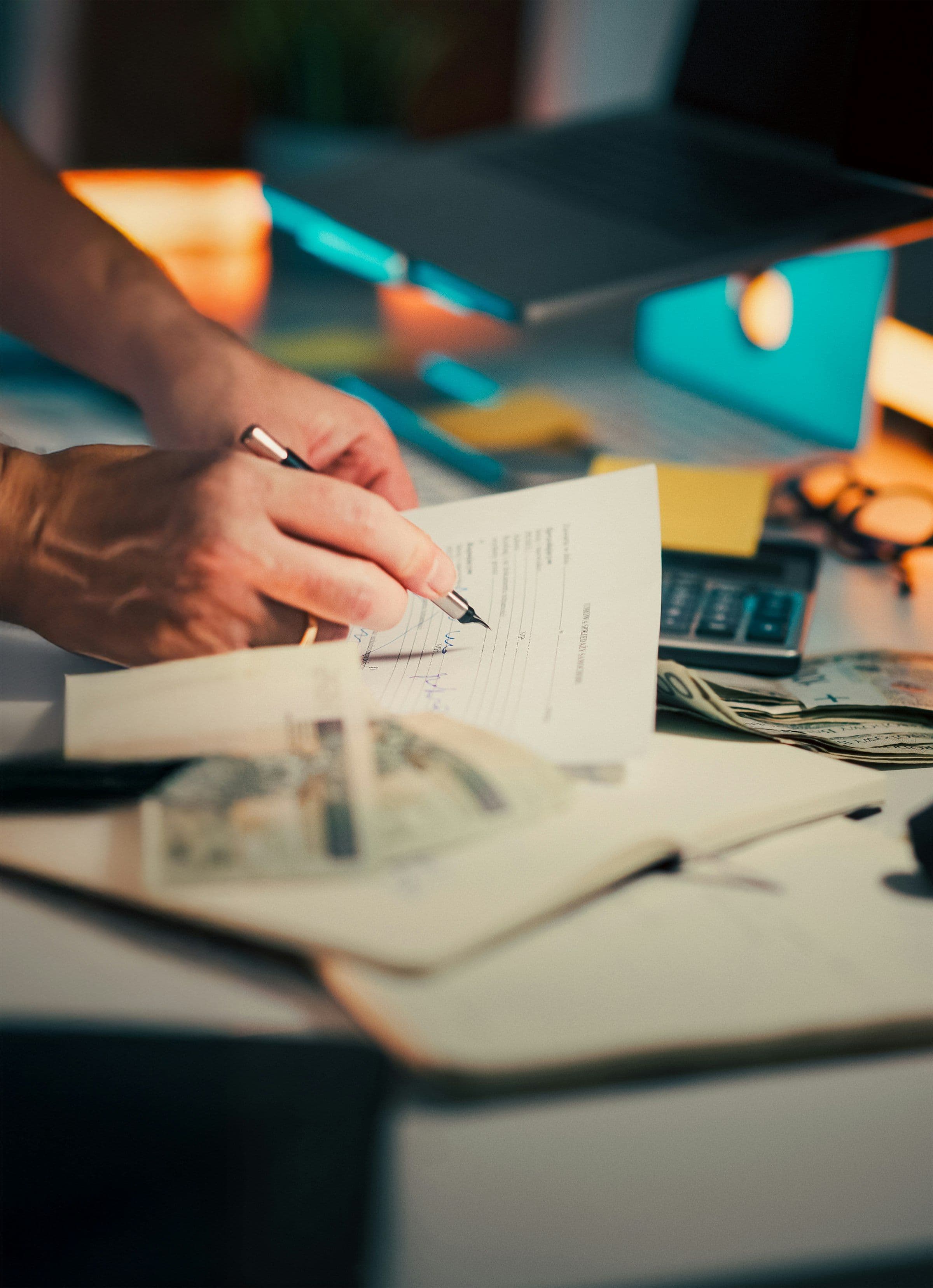 Hands signing a financial document at a desk