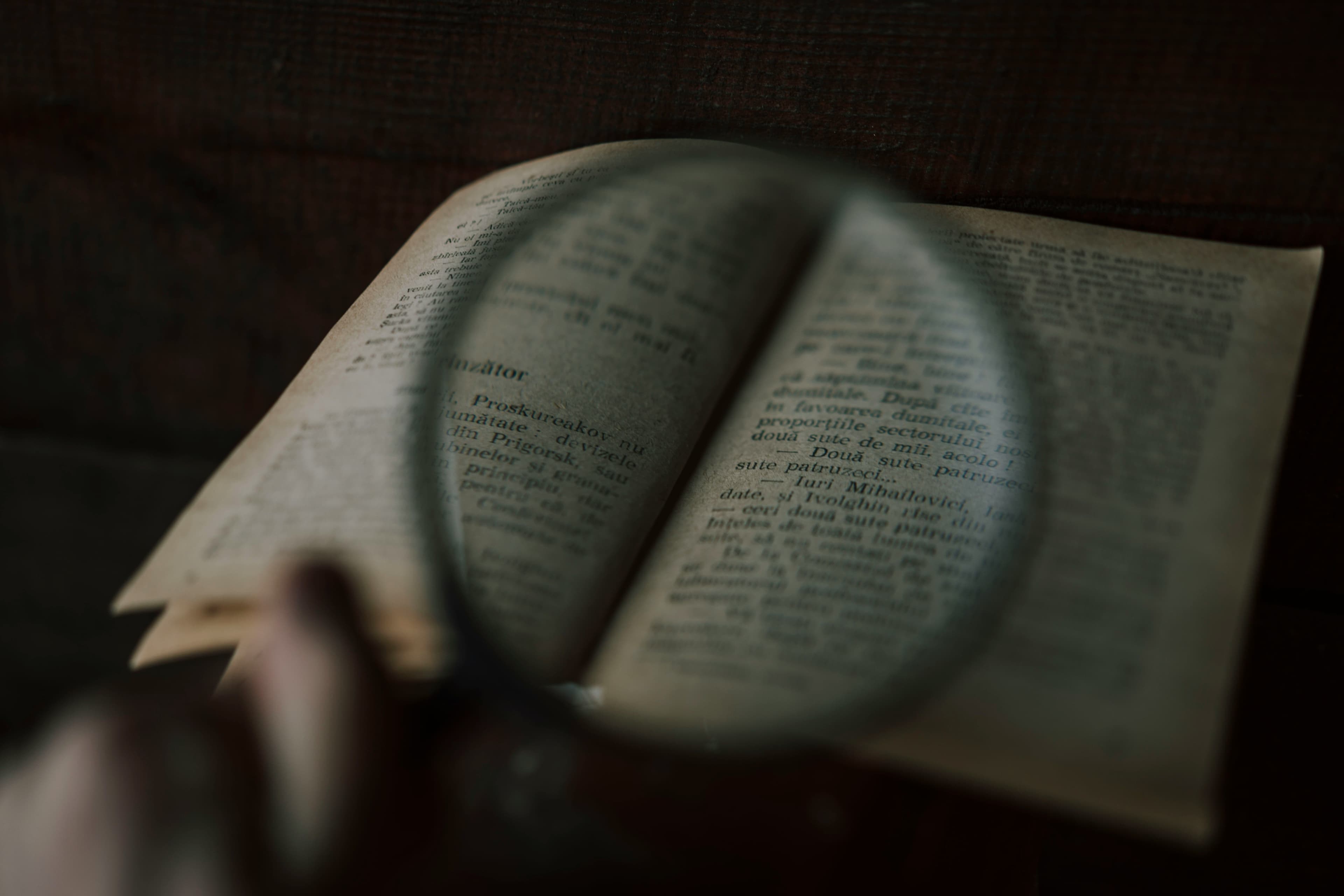 Magnifying glass over an open book, enlarging the printed text.