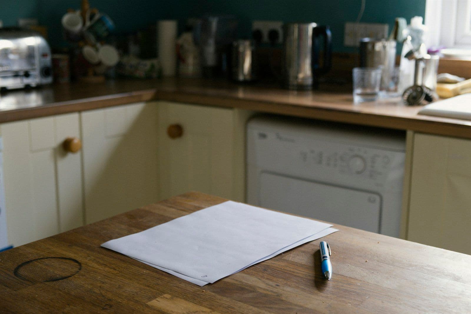 Blank paper and a pen on a wooden kitchen table
