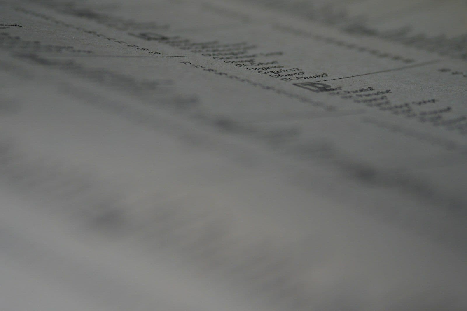 Blurred close-up of printed columns of data on a page, suggesting charts or numerical tracking