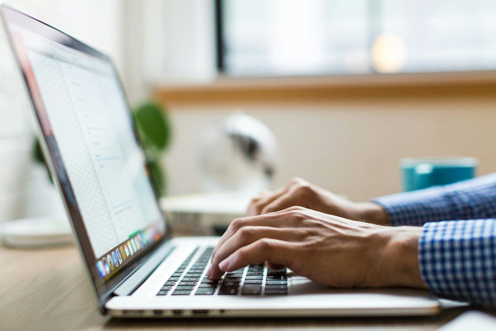 Person typing on silver MacBook, illustrating how Long Does Credit Repair Take.