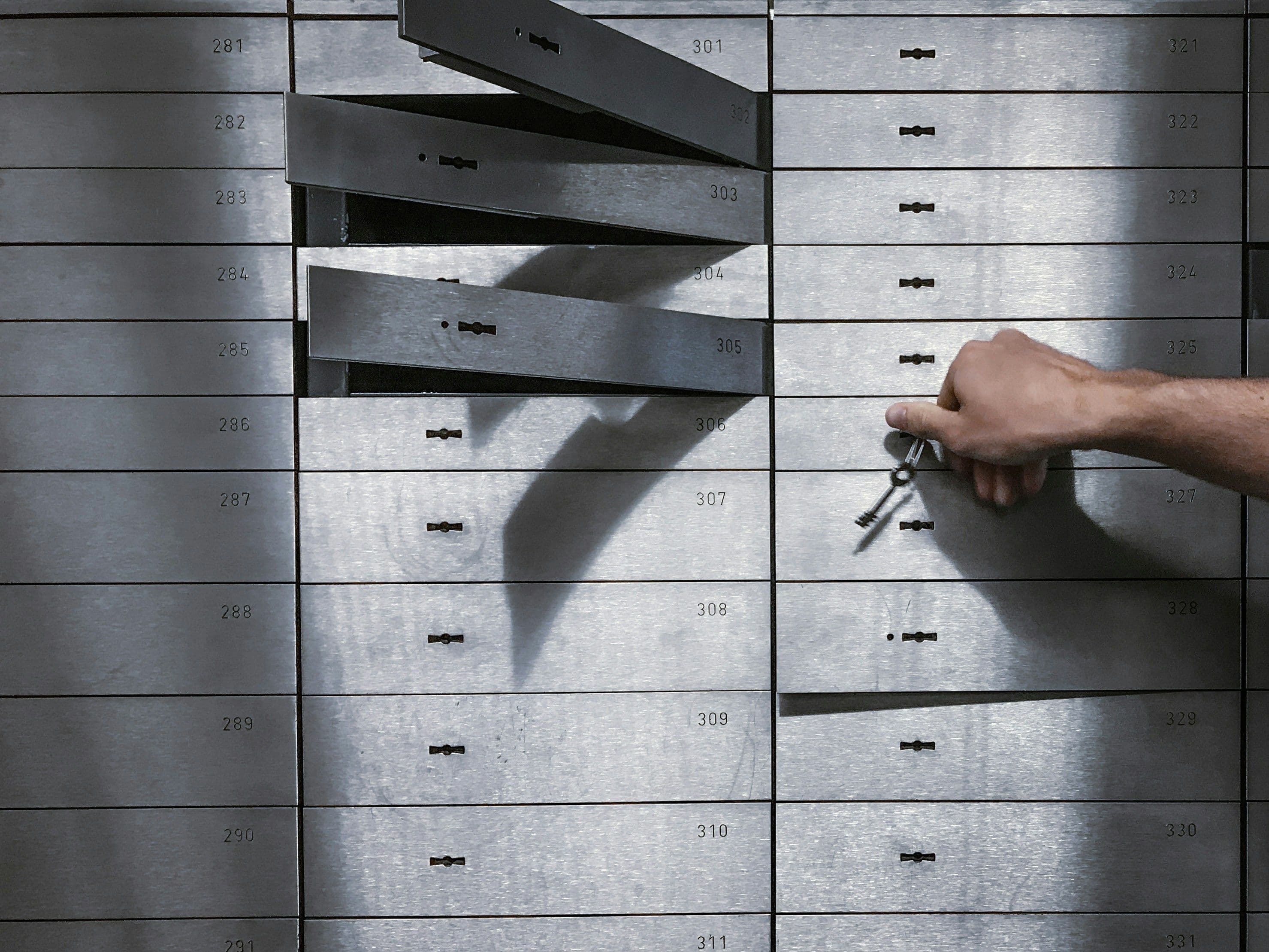 Open safe deposit boxes with a hand reaching in, illustrating the urgent steps to take after identity theft