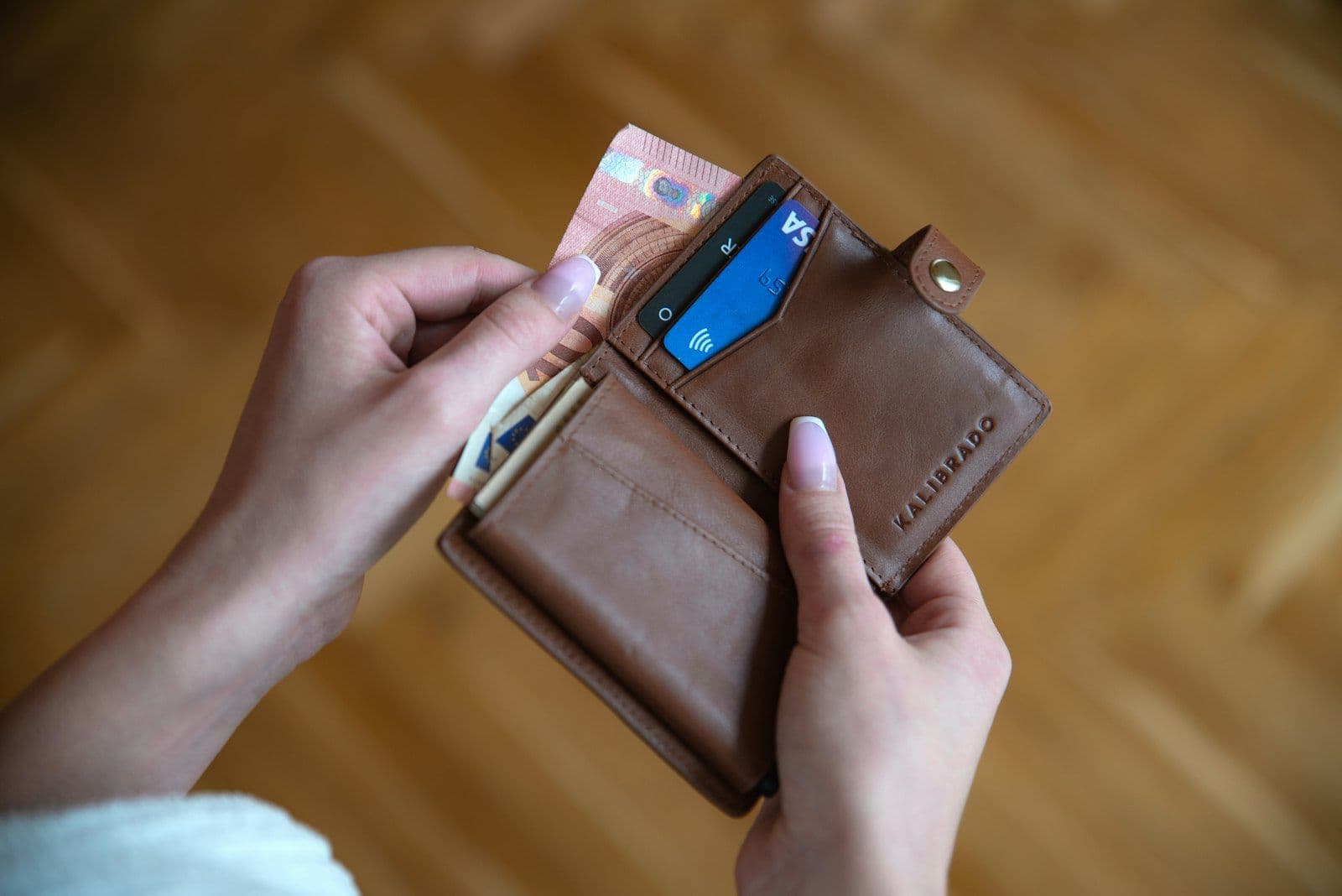 Person holding brown leather card wallet, illustrating how to Lower Credit Utilization.