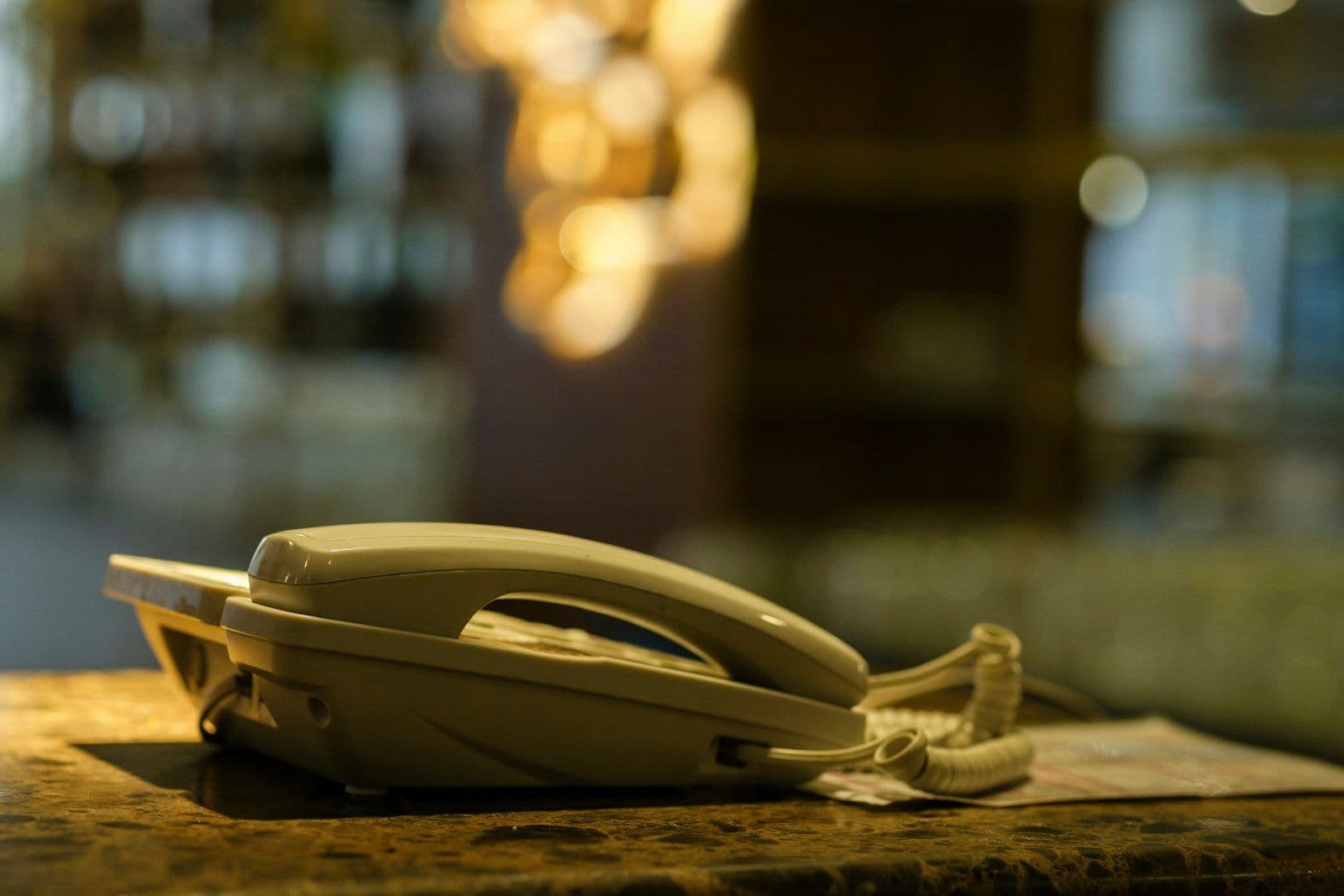 A landline phone resting on a stone counter in a dim room