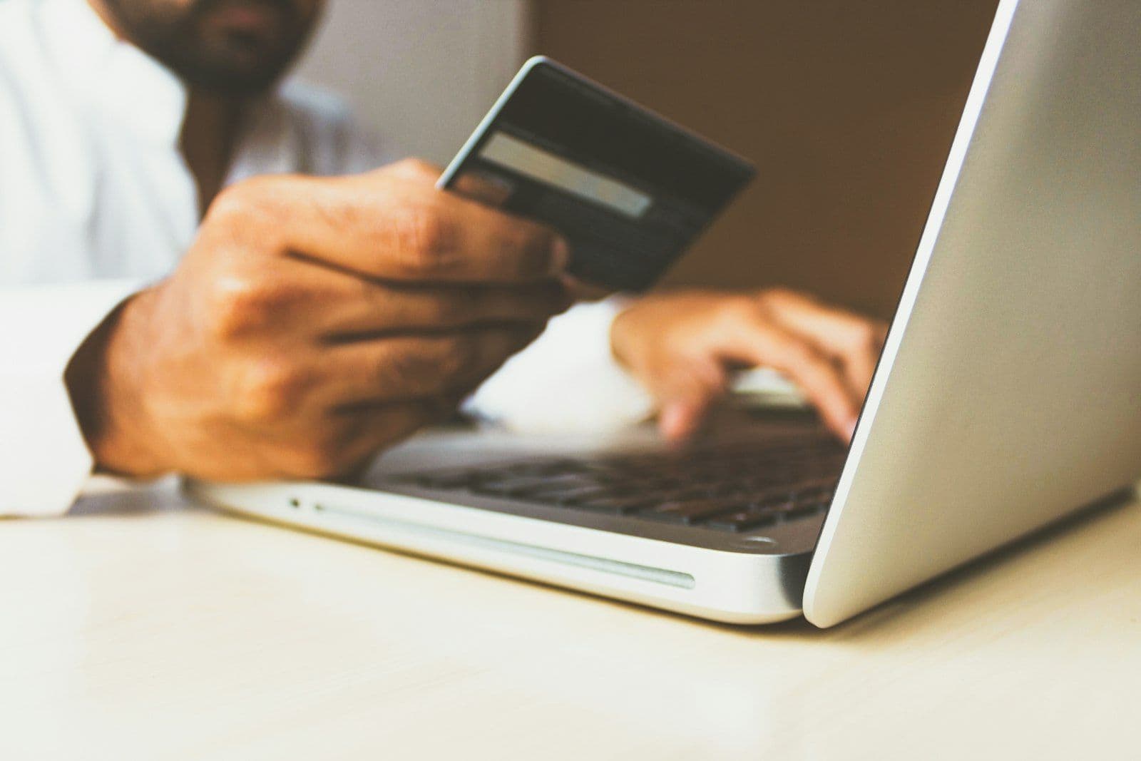 Credit card beside a laptop, illustrating how balance transfers affect credit.