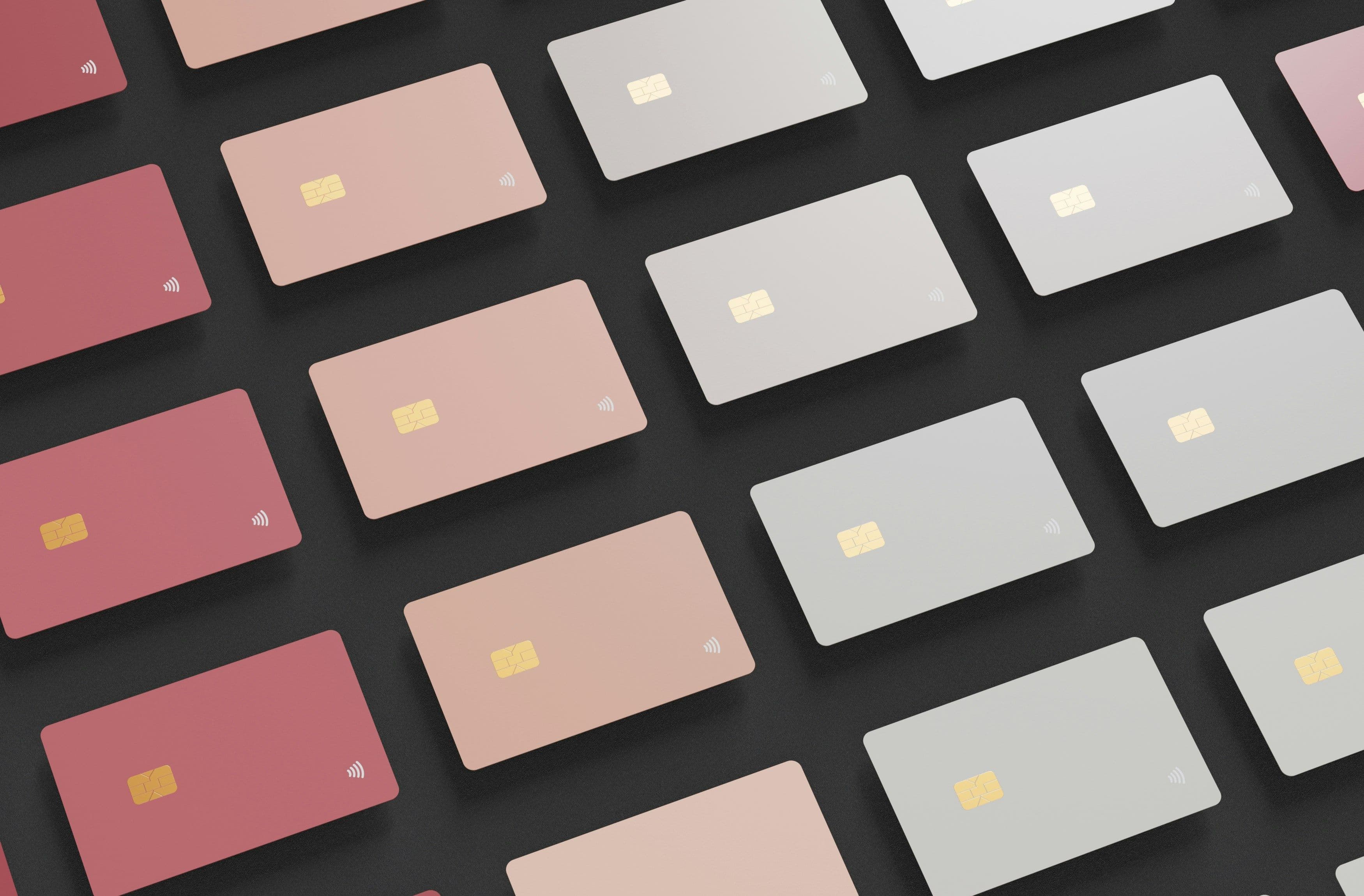 Stack of credit cards in muted reds, pinks, and grays on a dark surface, showing card options across credit score bands