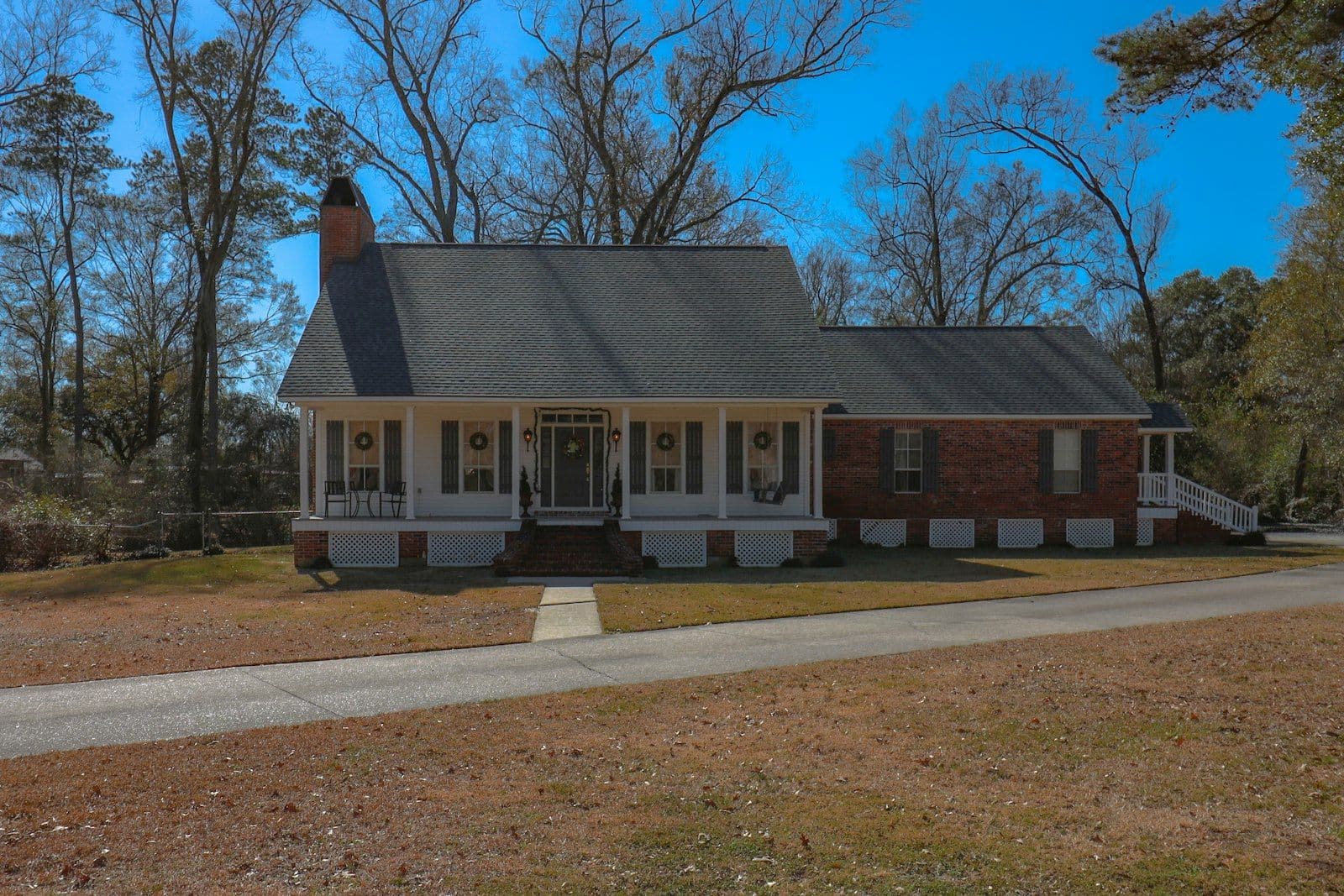 A charming brick and wood house with a wraparound porch, illustrating what Credit Score Do You Need to Buy a House.