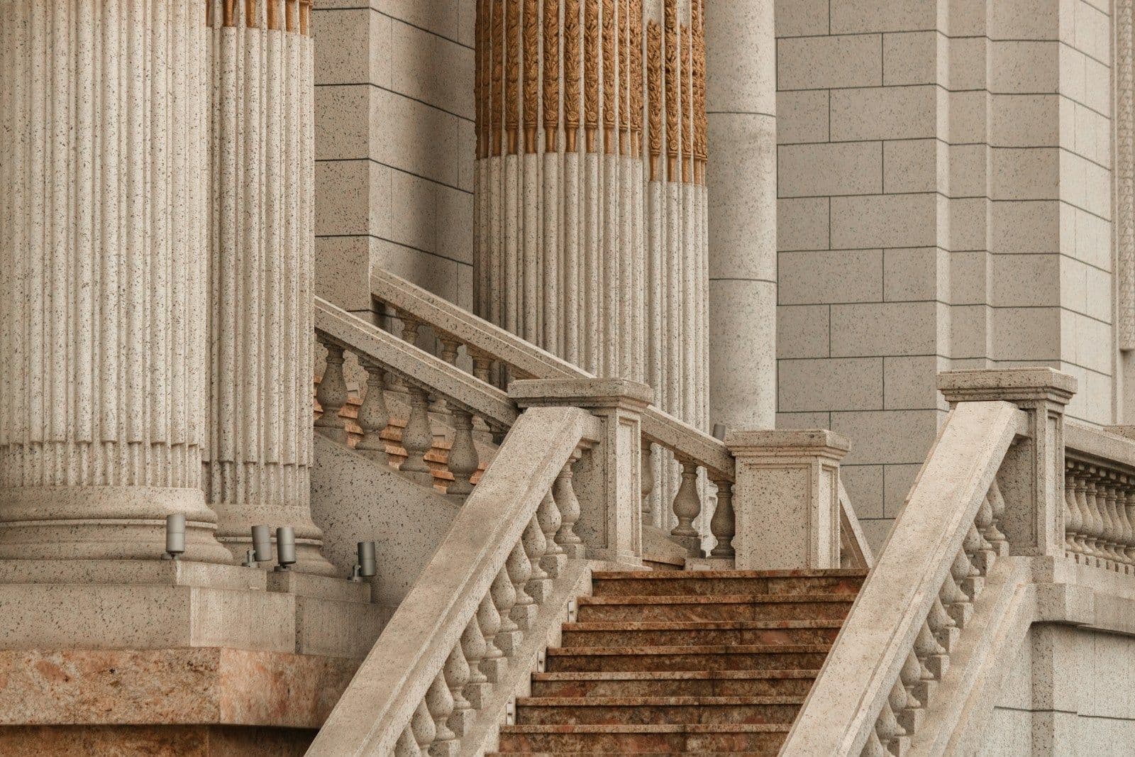 Stone staircase with balustrades leading up between large fluted columns of a courthouse-style building.