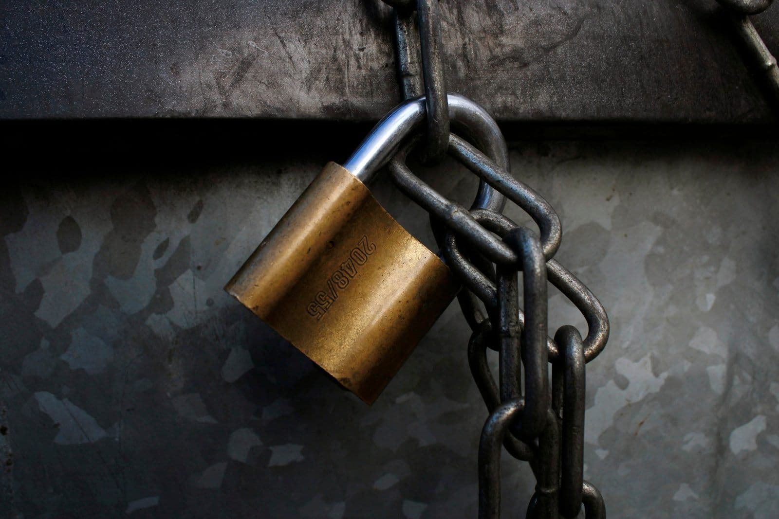 A brass padlock on a metal chain, illustrating a credit report security freeze.