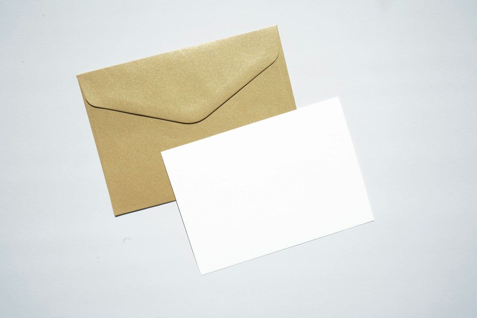 A kraft brown envelope and a blank white card lying side by side on a light gray surface